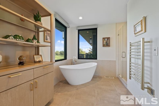 bathroom featuring tile patterned floors, separate shower and tub, tile walls, and radiator heating unit