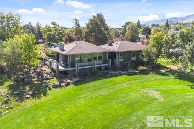 back of property featuring a yard and a mountain view