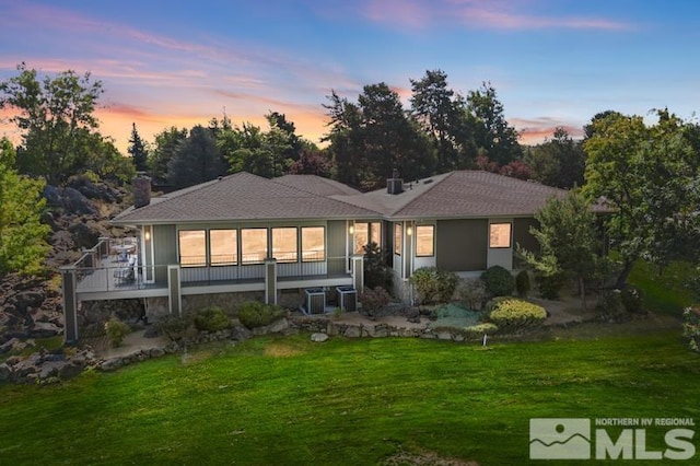 back house at dusk featuring a yard