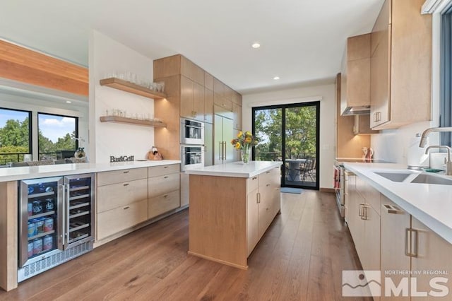 kitchen with wine cooler, sink, built in refrigerator, a center island, and light hardwood / wood-style floors