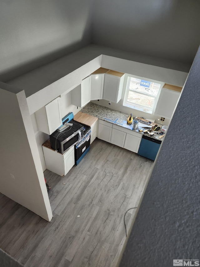 kitchen featuring vaulted ceiling, light hardwood / wood-style floors, and white cabinets