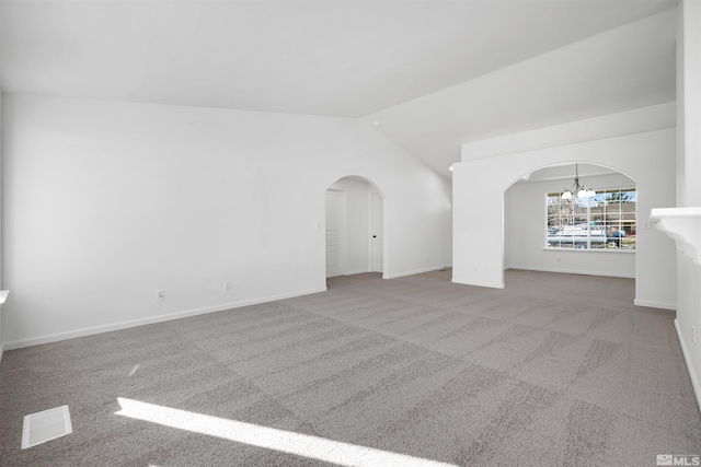 carpeted empty room featuring an inviting chandelier and vaulted ceiling