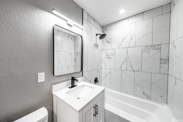 full bathroom featuring toilet, tiled shower / bath, and vanity