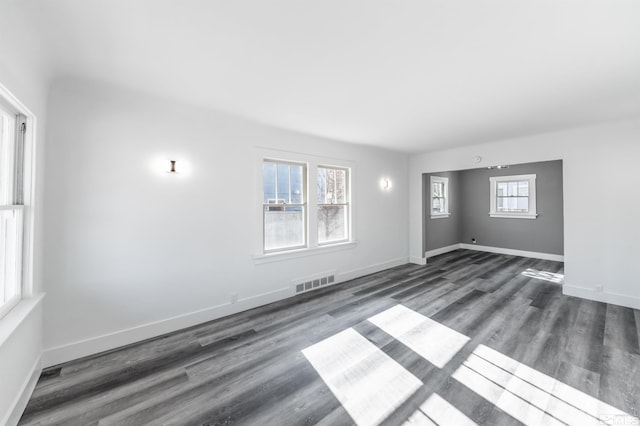 empty room featuring a healthy amount of sunlight and dark hardwood / wood-style floors