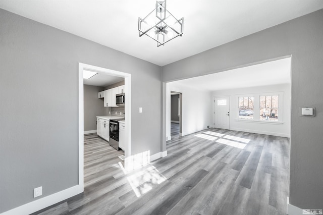 unfurnished living room with a notable chandelier and light wood-type flooring