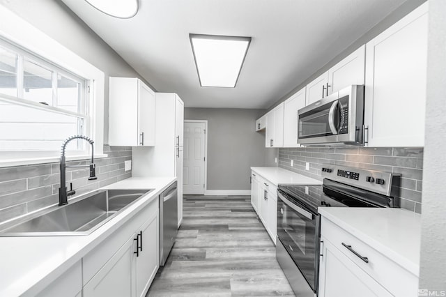 kitchen with sink, backsplash, white cabinets, and appliances with stainless steel finishes