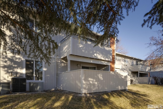 back of house with a balcony, central AC unit, and a yard