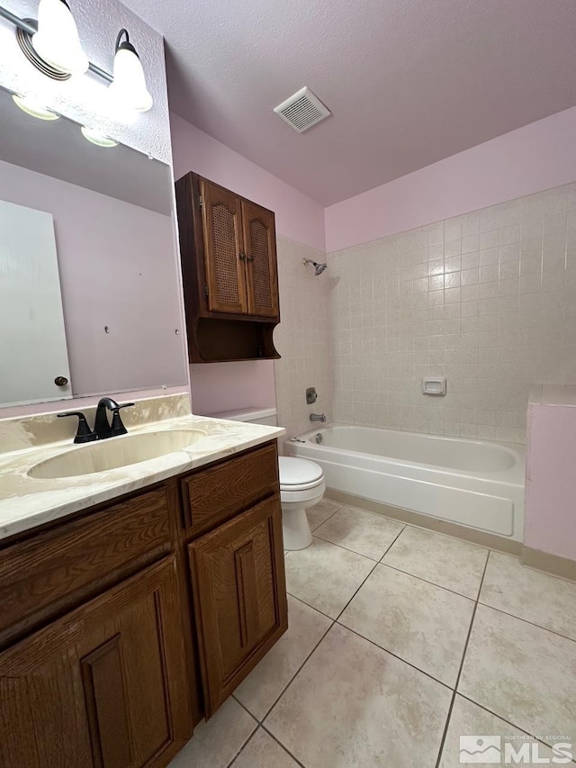 full bathroom with a textured ceiling, tiled shower / bath, tile patterned flooring, vanity, and toilet