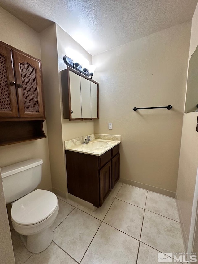 bathroom with vanity, toilet, tile patterned floors, and a textured ceiling