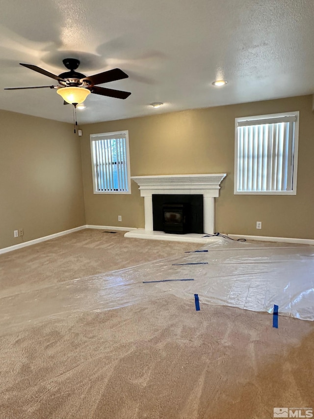 unfurnished living room featuring ceiling fan, carpet flooring, and a textured ceiling