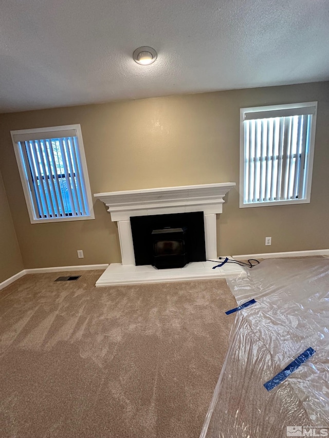 unfurnished living room with carpet floors and a textured ceiling