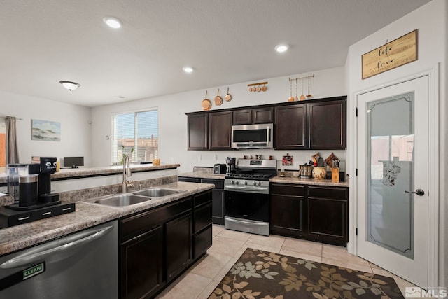 kitchen with dark brown cabinets, sink, stainless steel appliances, and light tile patterned flooring