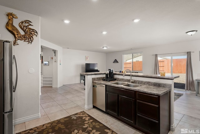 kitchen featuring sink, dark brown cabinets, an island with sink, stainless steel appliances, and light tile patterned flooring