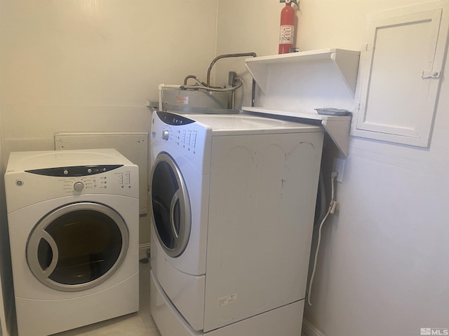 clothes washing area featuring light tile patterned flooring, water heater, and washer and dryer