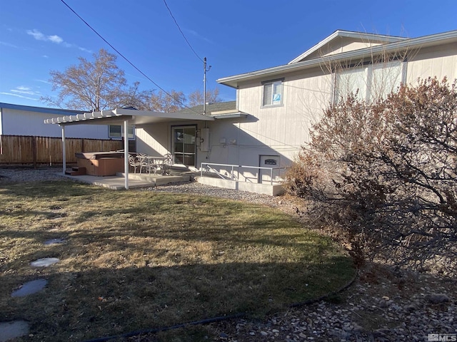 rear view of property featuring a patio area, a yard, and a hot tub