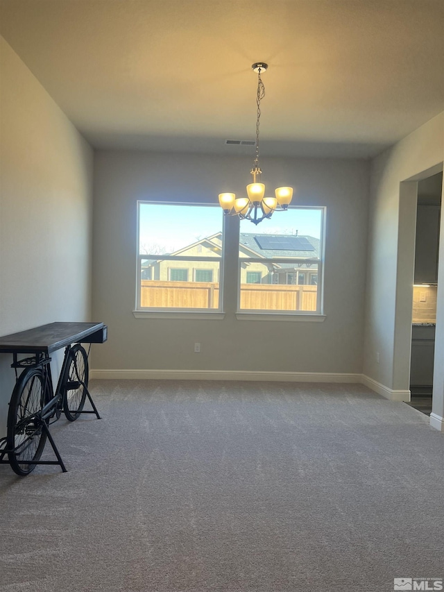 unfurnished dining area featuring an inviting chandelier and carpet flooring