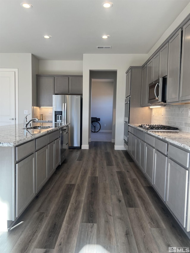 kitchen with dark hardwood / wood-style flooring, stainless steel appliances, tasteful backsplash, sink, and gray cabinetry