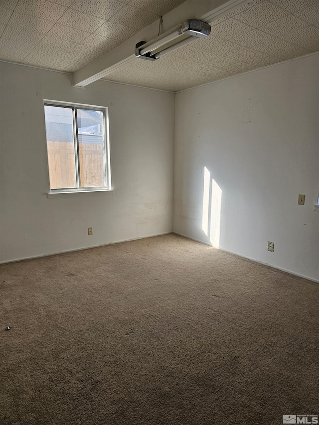 empty room featuring carpet floors and beamed ceiling