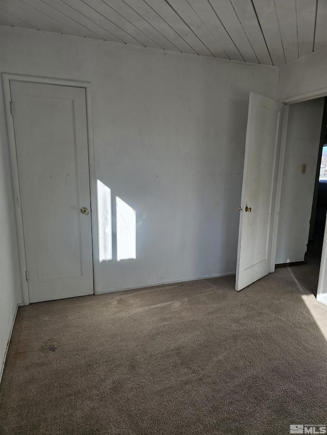 carpeted spare room featuring wooden ceiling