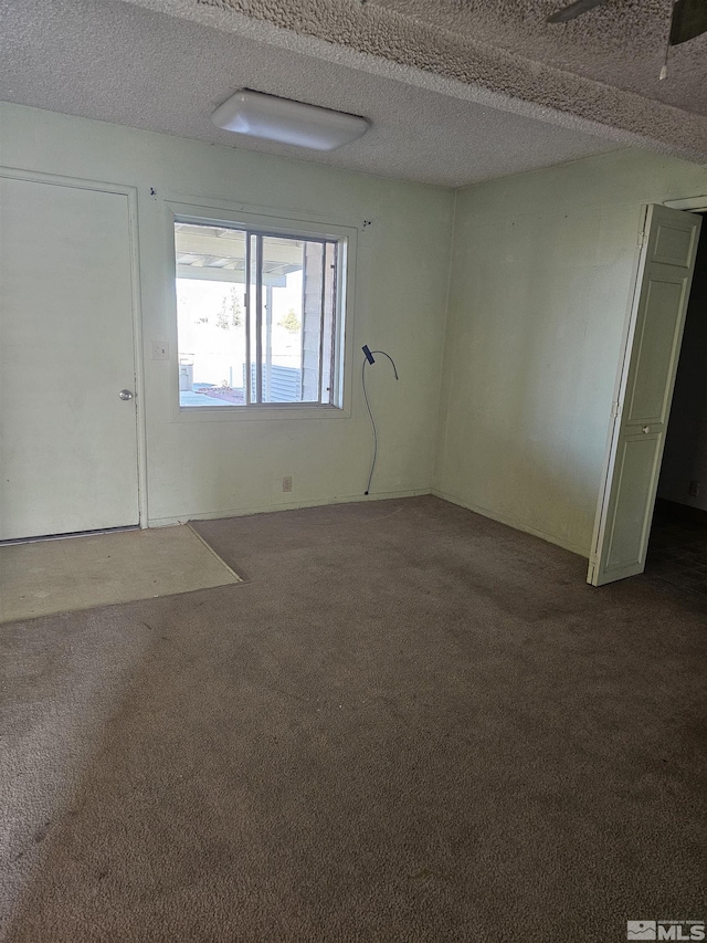 carpeted empty room featuring a textured ceiling