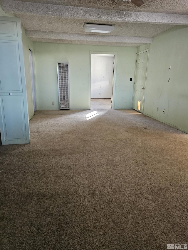 unfurnished room featuring beam ceiling, ceiling fan, light colored carpet, and a textured ceiling