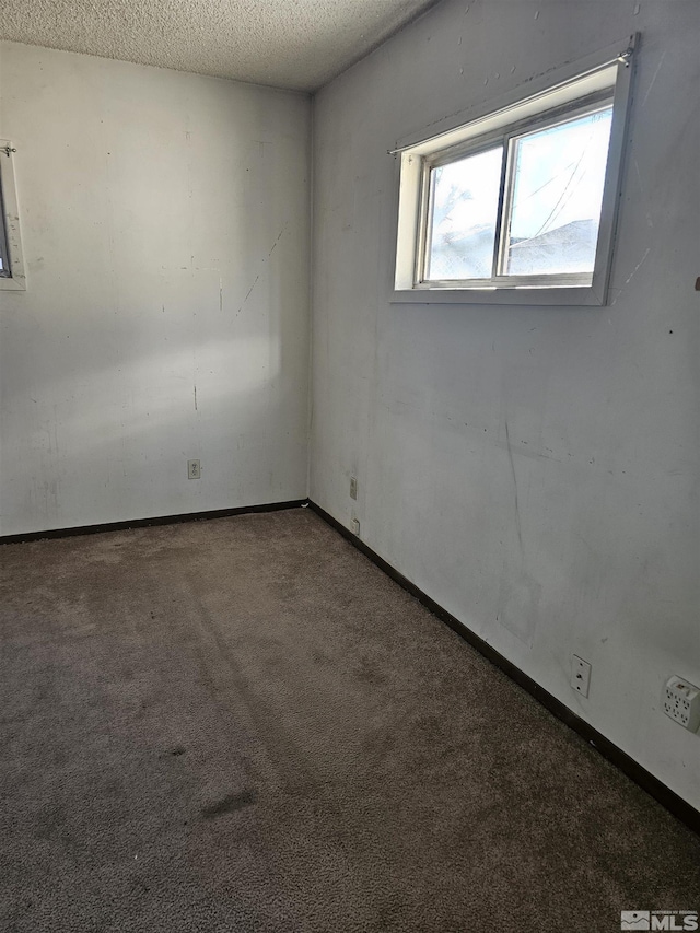carpeted empty room featuring a textured ceiling