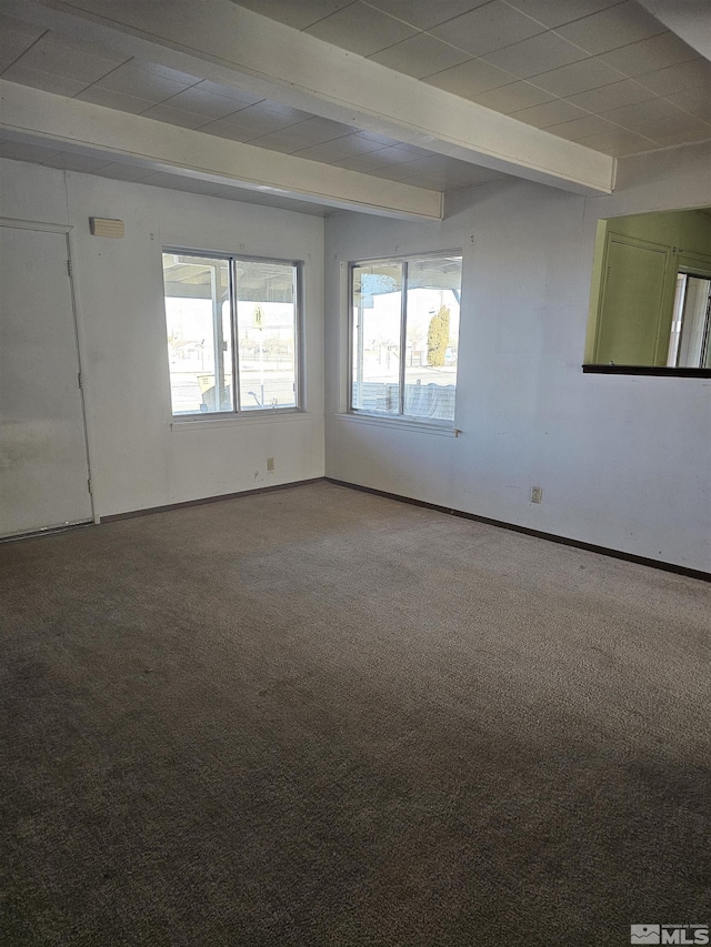 carpeted empty room featuring beamed ceiling