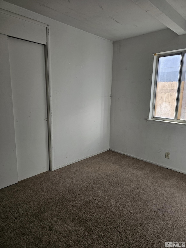 unfurnished bedroom with carpet and beam ceiling