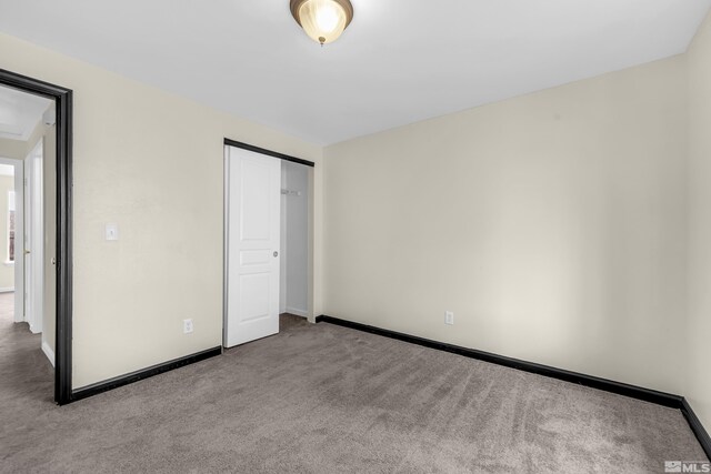 unfurnished bedroom featuring light colored carpet and a closet