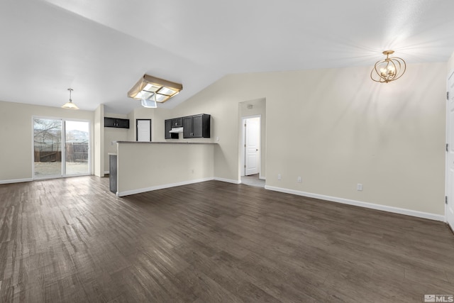 unfurnished living room with vaulted ceiling, dark hardwood / wood-style floors, and a chandelier