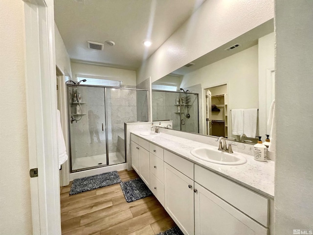 bathroom with a shower with shower door, hardwood / wood-style floors, and vanity