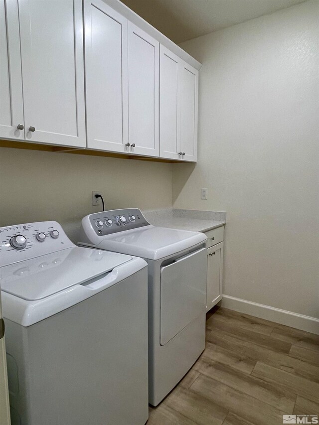 laundry area with cabinets, light hardwood / wood-style flooring, and washing machine and clothes dryer