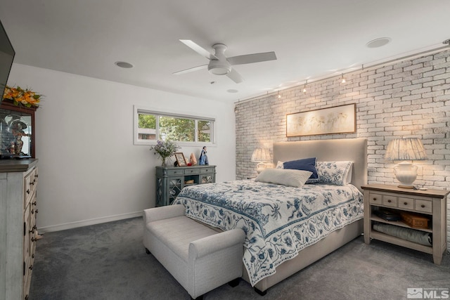 bedroom with ceiling fan, rail lighting, dark carpet, and brick wall
