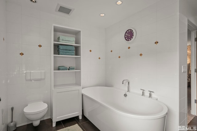 bathroom with tile patterned flooring, tile walls, built in features, a bathing tub, and toilet