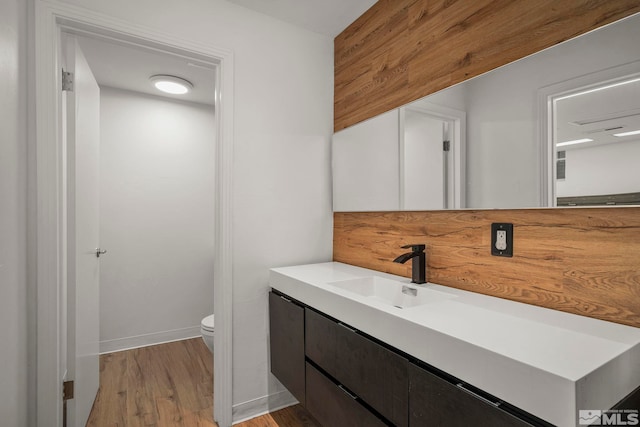 bathroom with hardwood / wood-style flooring, toilet, and vanity