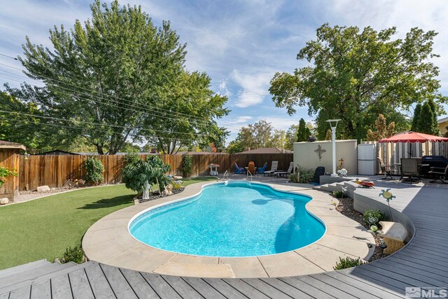 view of swimming pool with a yard, a deck, and a patio