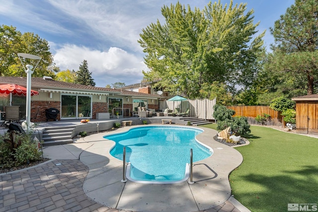 view of pool featuring a patio area, a grill, and a lawn