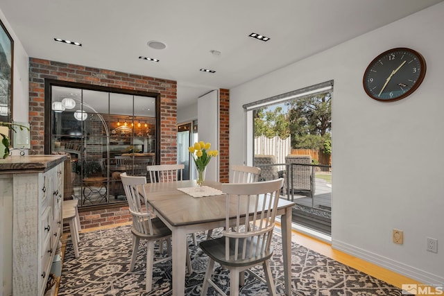 dining room featuring wood-type flooring and brick wall