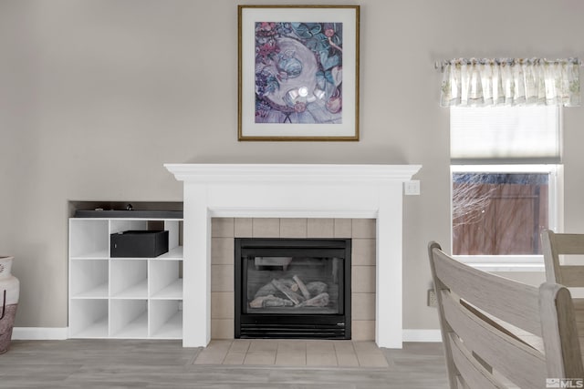 interior details featuring wood-type flooring and a tiled fireplace