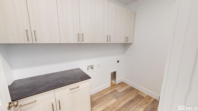 washroom featuring electric dryer hookup, cabinets, washer hookup, and light wood-type flooring