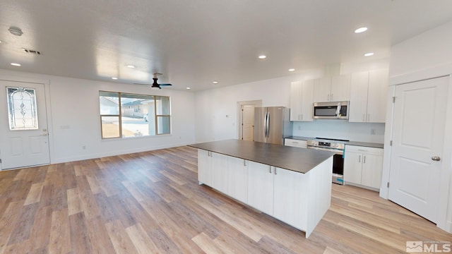 kitchen featuring light hardwood / wood-style floors, white cabinets, appliances with stainless steel finishes, and a center island