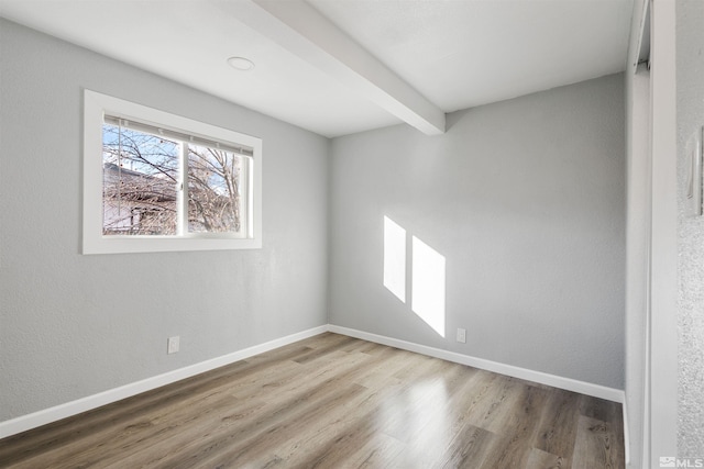 empty room featuring hardwood / wood-style floors and beam ceiling