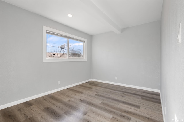 empty room featuring wood-type flooring and beam ceiling