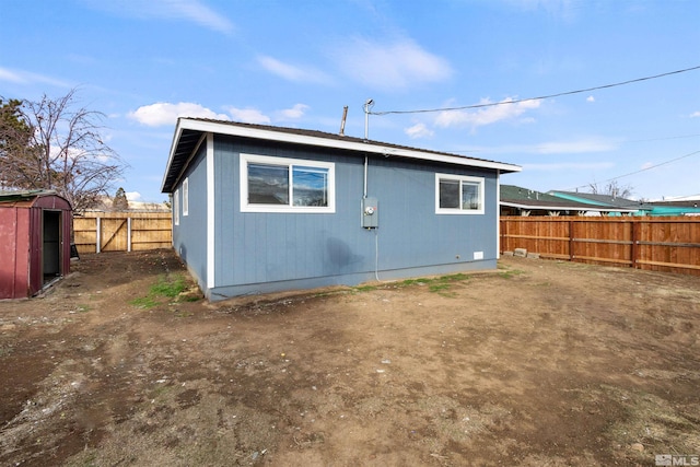 back of house with a storage shed