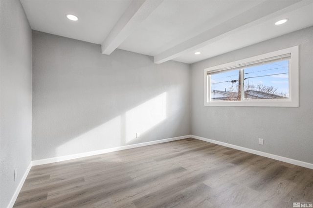 spare room featuring wood-type flooring and beam ceiling