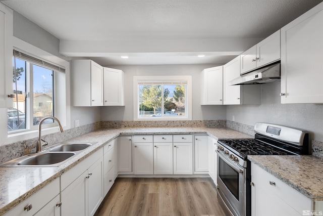 kitchen with white cabinetry, gas stove, sink, and light stone counters