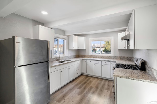 kitchen with appliances with stainless steel finishes, sink, white cabinets, light stone counters, and light hardwood / wood-style flooring