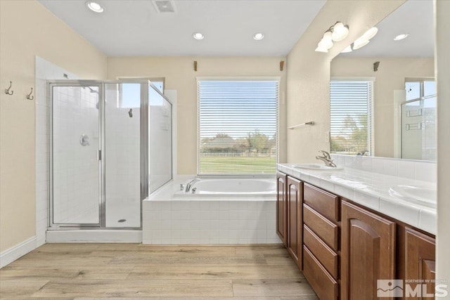 bathroom with vanity, independent shower and bath, hardwood / wood-style floors, and a wealth of natural light