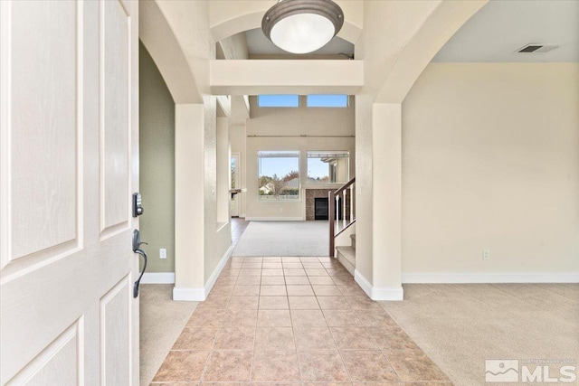 carpeted entryway featuring a towering ceiling