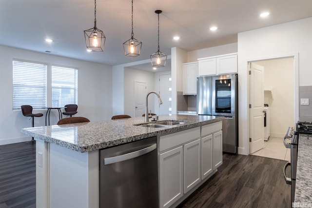 kitchen featuring dark wood-type flooring, sink, white cabinetry, appliances with stainless steel finishes, and a kitchen island with sink